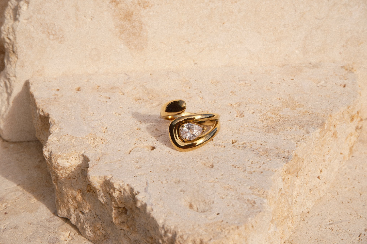 Gold ring with a diamond on a beige stone surface
