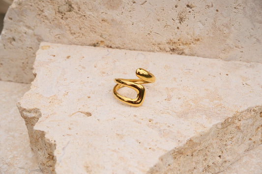 Gold ring on a textured beige stone surface