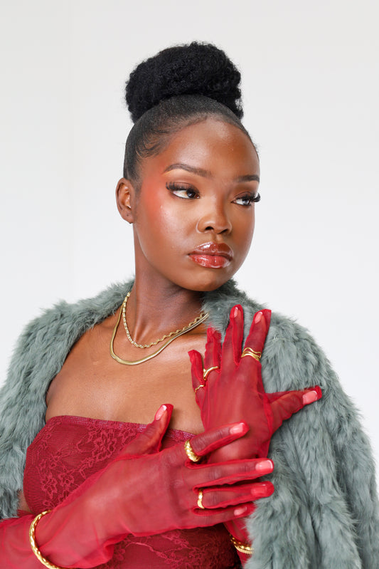 Woman wearing red gloves and a gray fur coat against a white background