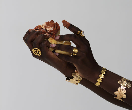 Hand with gold jewelry on a gray background