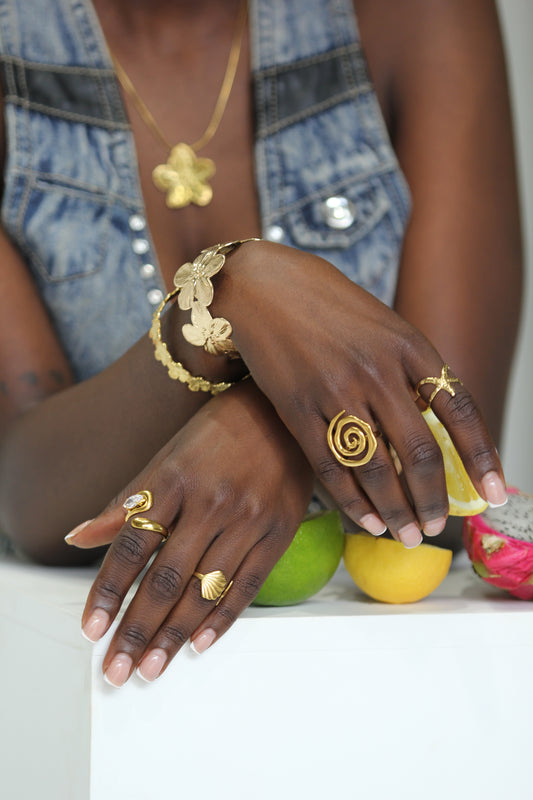 Sol & Aura - Woman in denim vest wearing holding a lemon and wearing gold jewellery