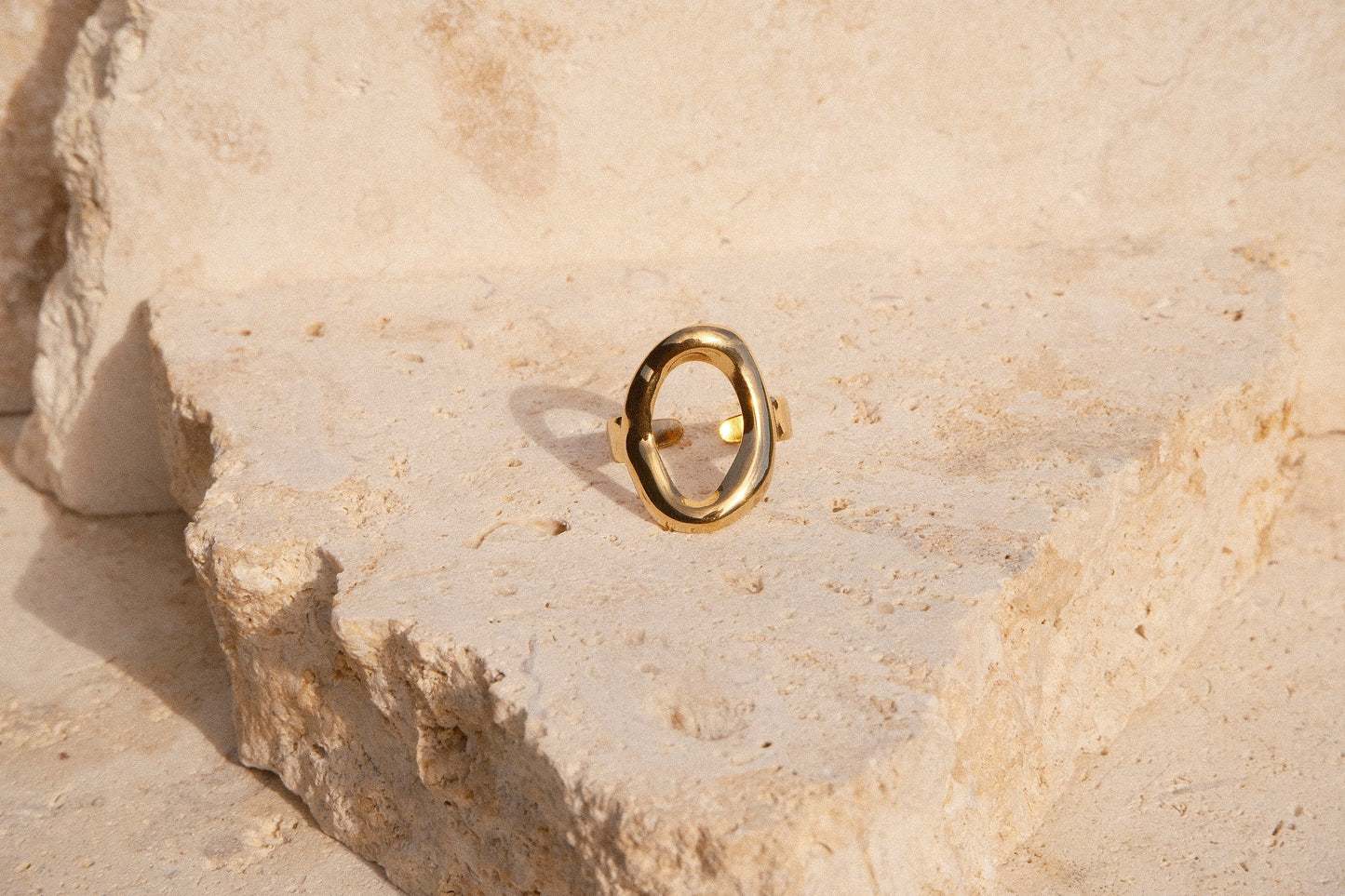 Gold ring on a textured beige stone surface