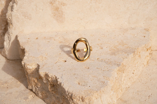 Gold ring on a textured beige stone surface