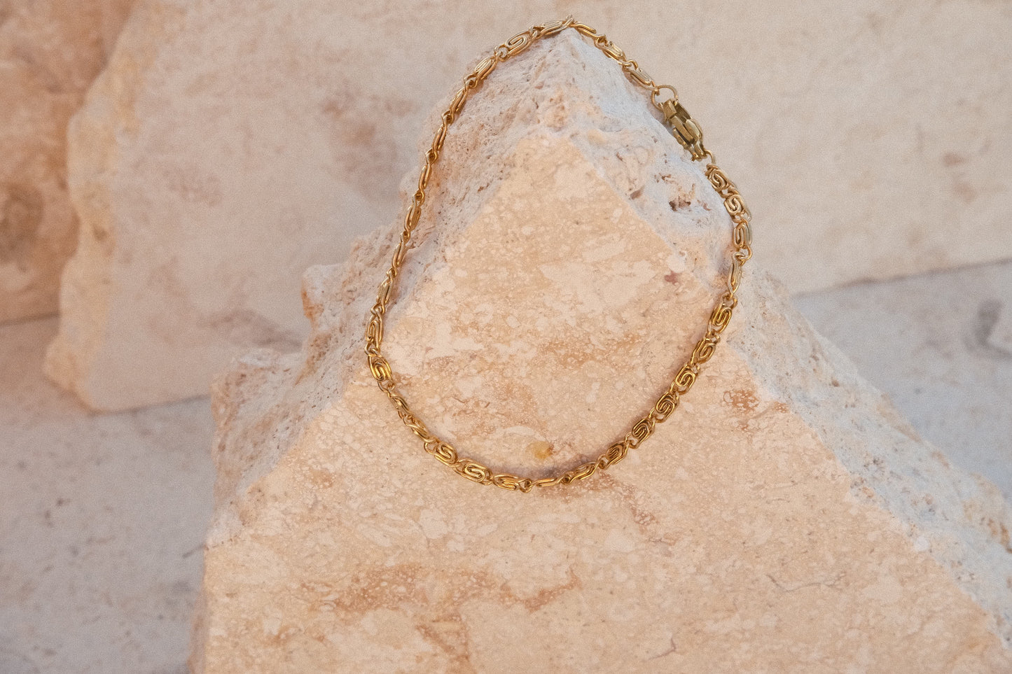 Gold chain bracelet on a textured stone surface