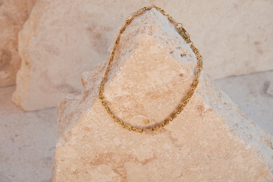 Gold chain bracelet on a textured stone surface