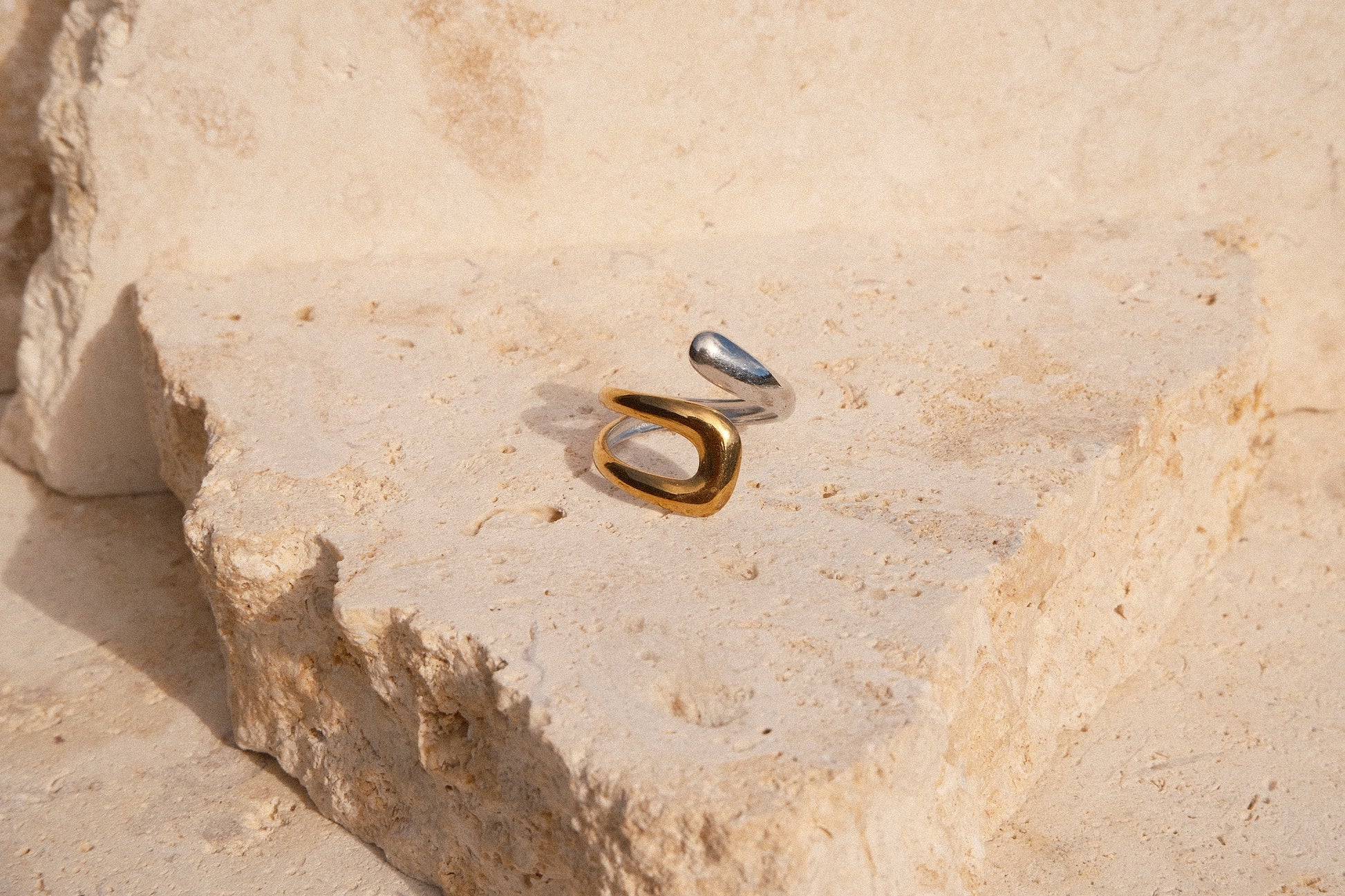 Gold and silver ring on a textured stone surface