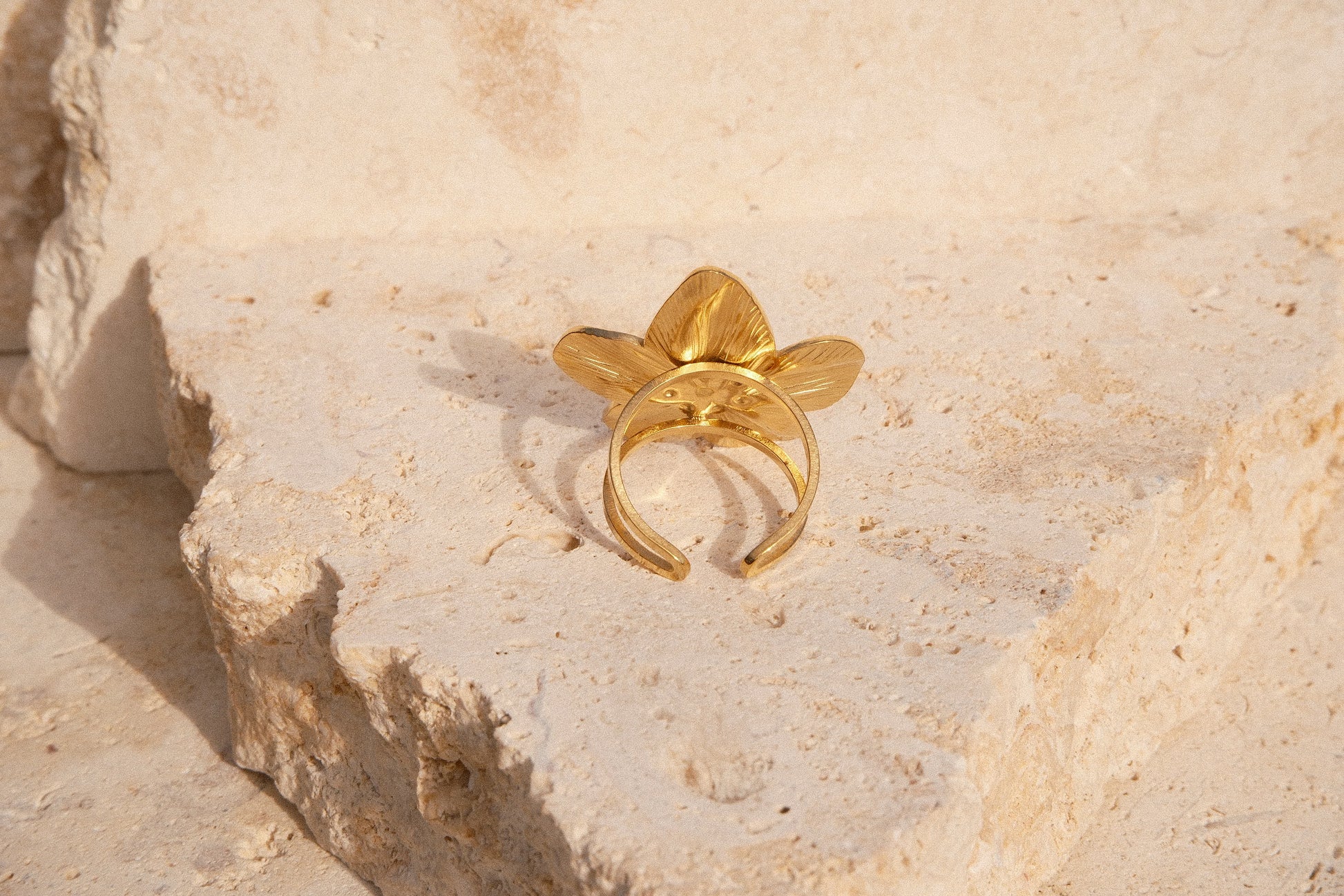 Gold ring with leaf design on a textured stone surface