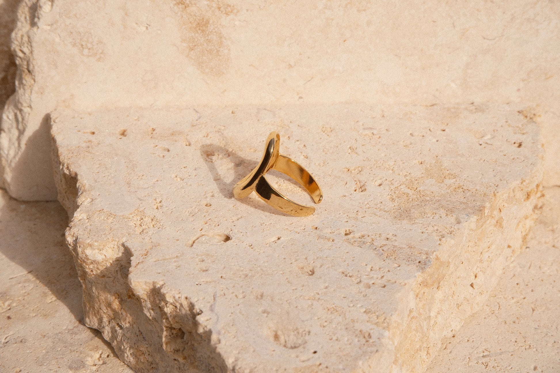 Gold ring on a textured beige stone surface