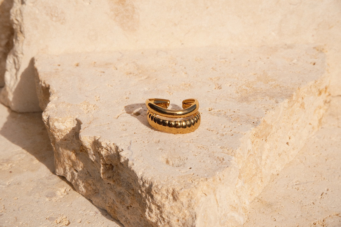 Gold ring on a textured beige stone surface