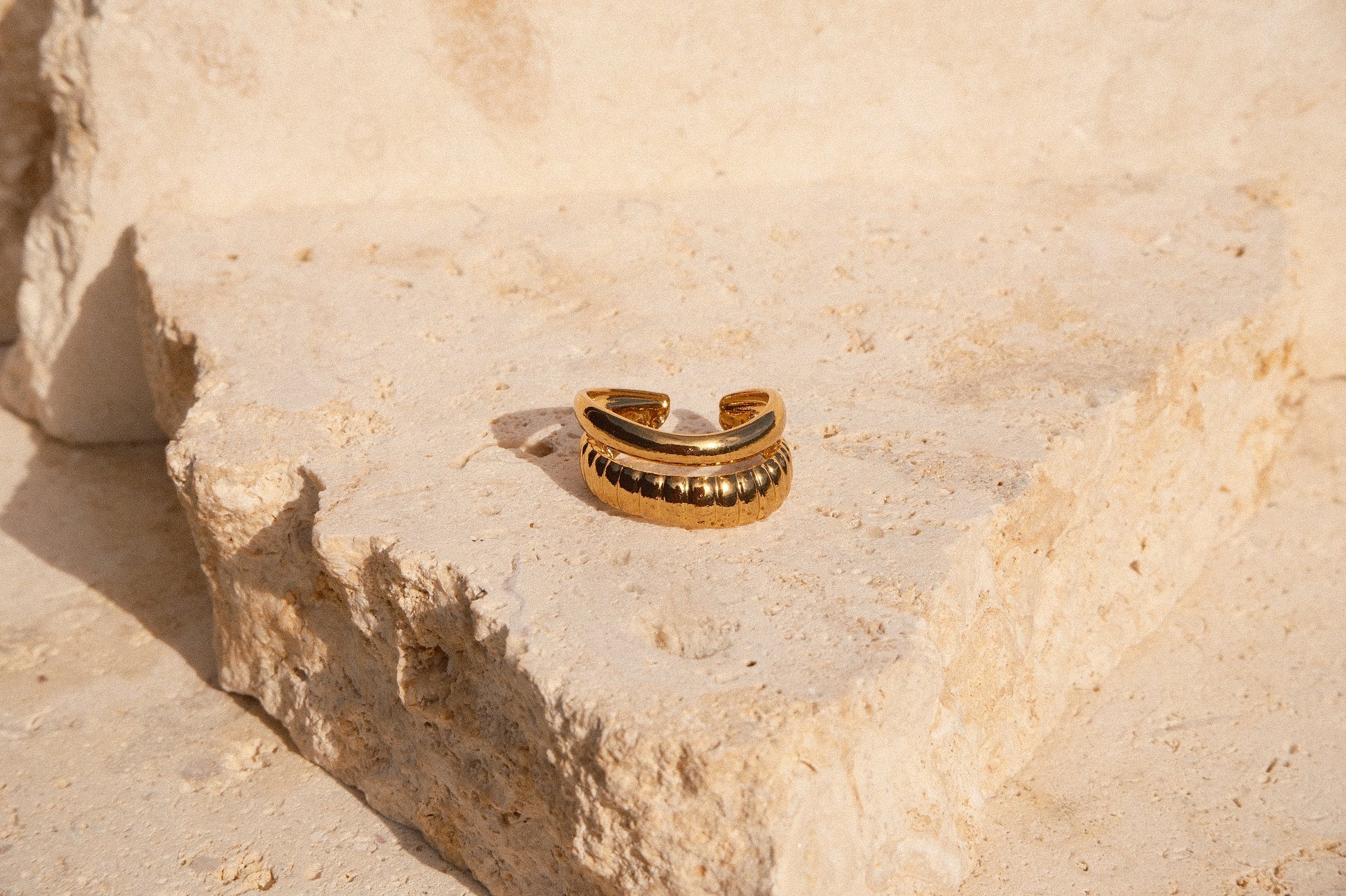 Gold ring on a textured beige stone surface