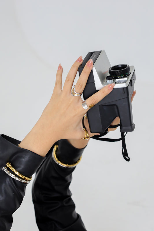 Hand holding a vintage Polaroid camera against a plain background