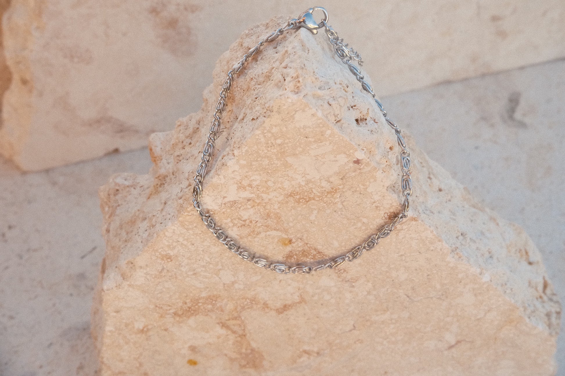 Silver chain bracelet on a textured stone surface