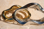 Two metallic claw clips, one gold and one silver, on a textured surface.
