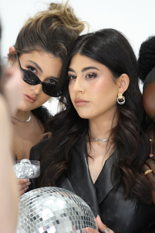 Sol & Aura - Alaska earrings on woan with black hair holding a disco ball, next to another woman in black sunglasses holding a glass of small disco balls