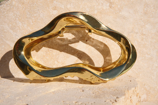 Gold claw clip on a textured beige surface