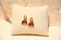Sol & Aura - Brown and beige glass crystal-like gemstone drop earrings pinned onto cushion against stone background