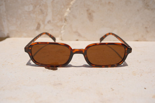 Sol & Aura - Carrie Sunglasses - Brown, tortoise shell detailing. Narrow rectangular lens shape with brown lens on stone surface