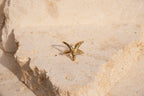 Gold starfish-shaped ring on a textured beige surface