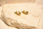 Sol & Aura - Close up of gold stud earrings lying on natural stone surface