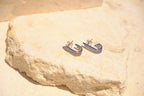 Sol & Aura - Close up of silver stud earrings lying on natural stone surface