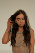 Woman wearing a beige headscarf and dress against a plain background