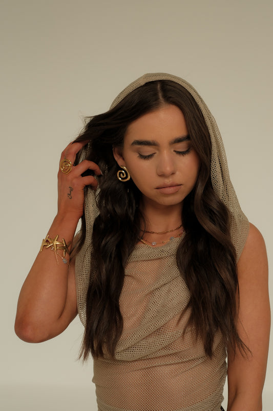 Woman wearing a beige headscarf and dress against a plain background