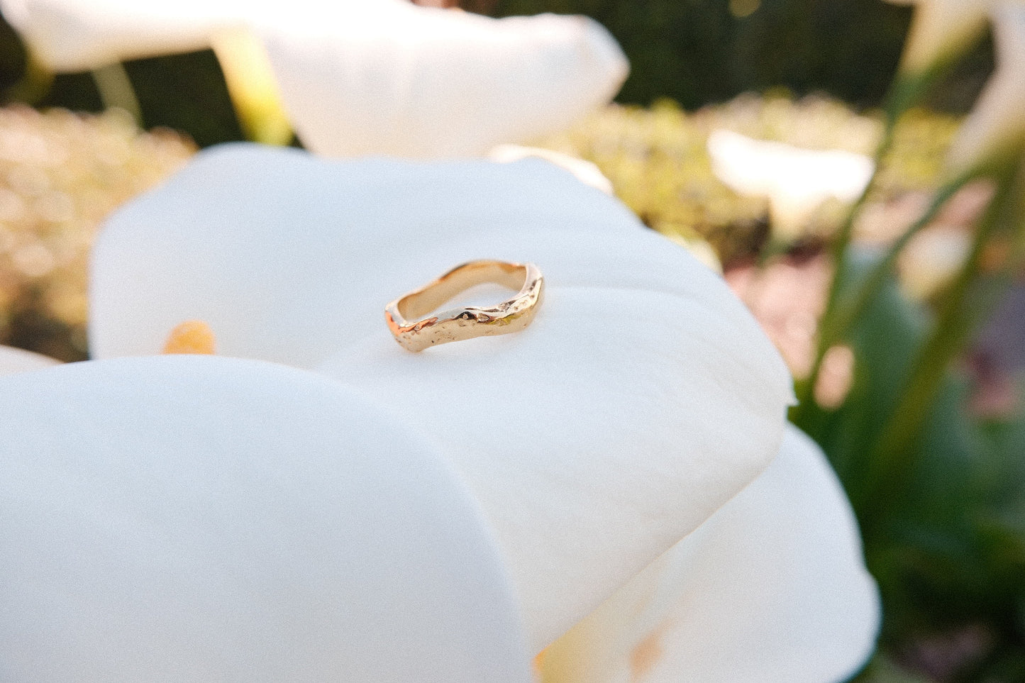 Gold ring on a white flower with a blurred natural background