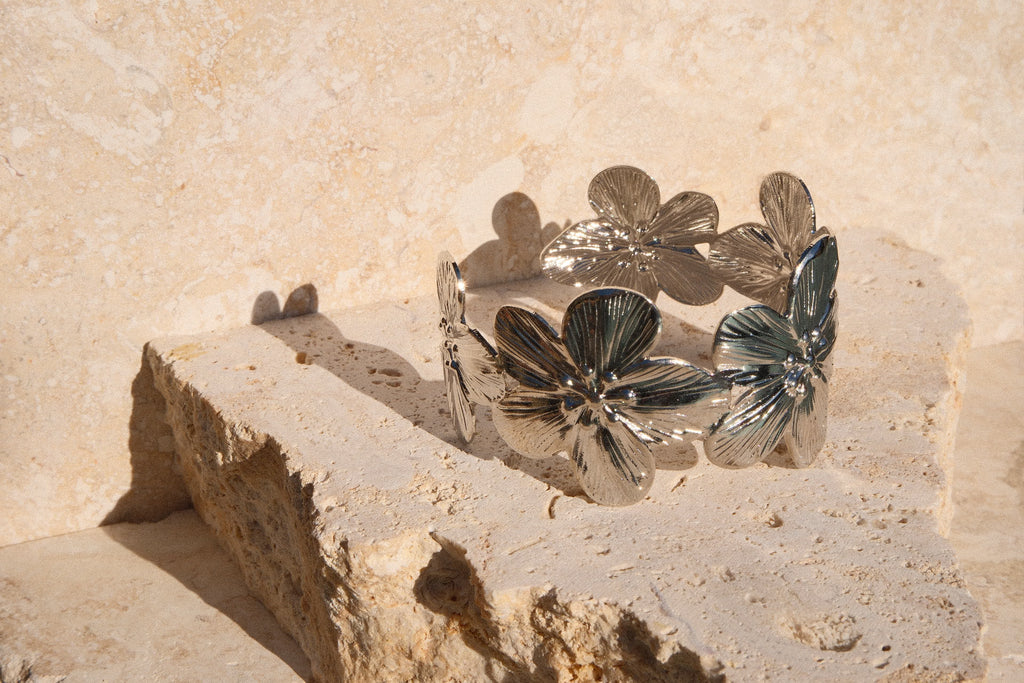 Silver bracelet with leaf designs on a stone surface