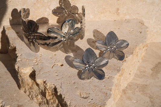 Silver floral jewelry set on a stone surface