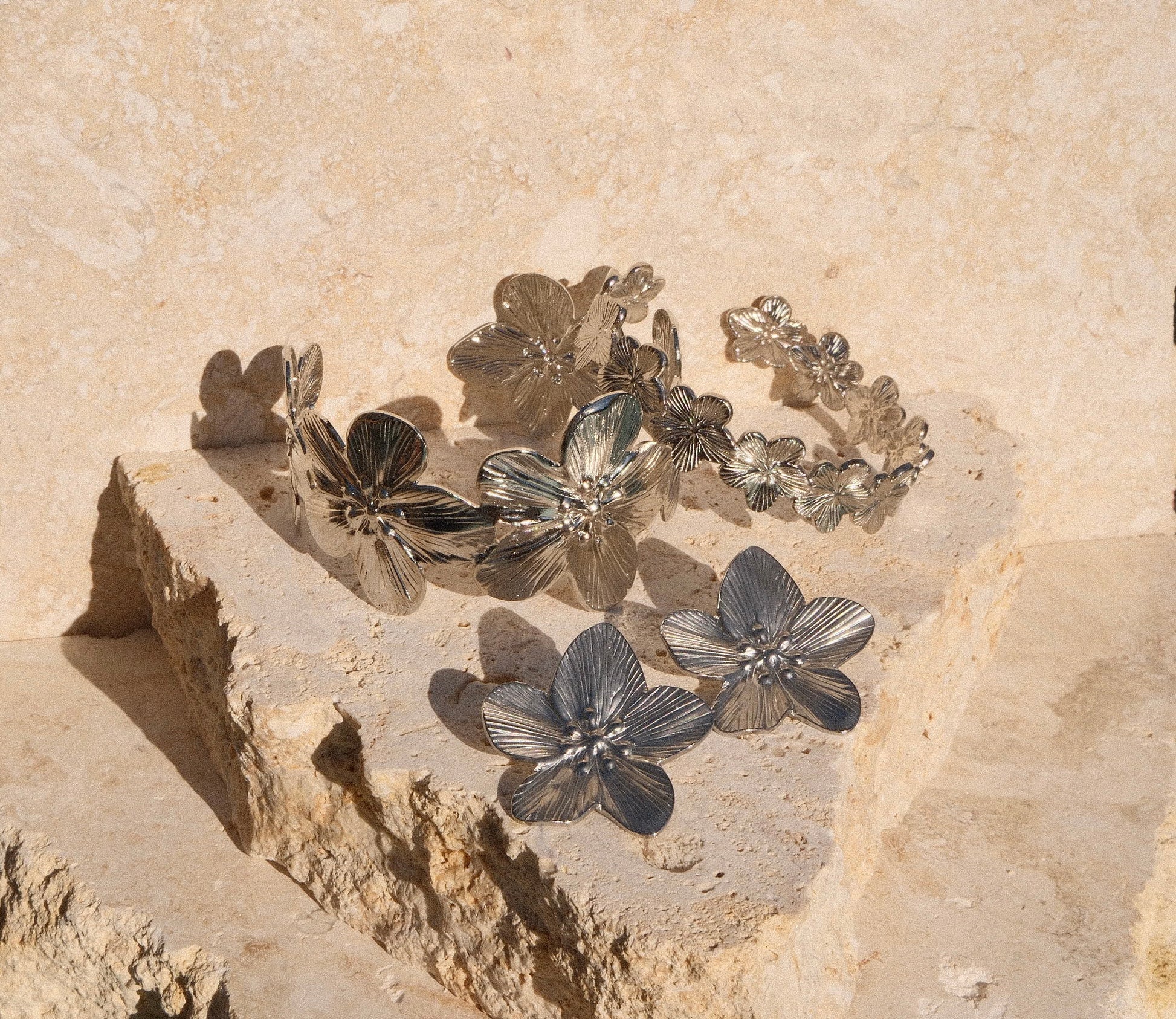 Silver floral bracelet on a textured stone surface