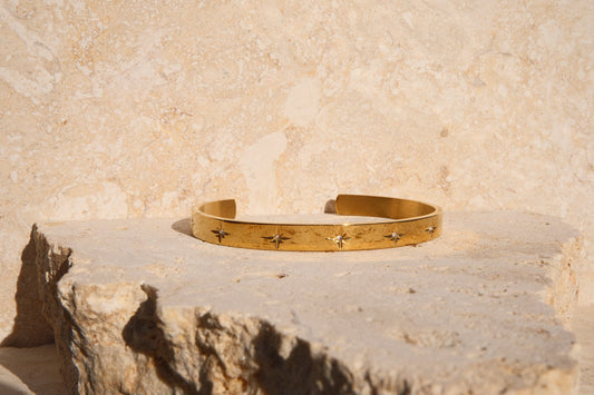 Gold bracelet on a textured stone surface with a neutral background