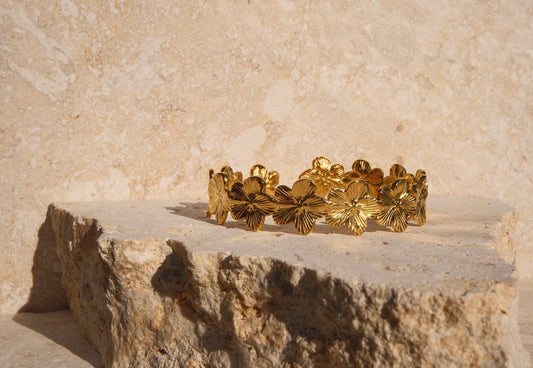 Gold bracelet with floral design on a stone surface