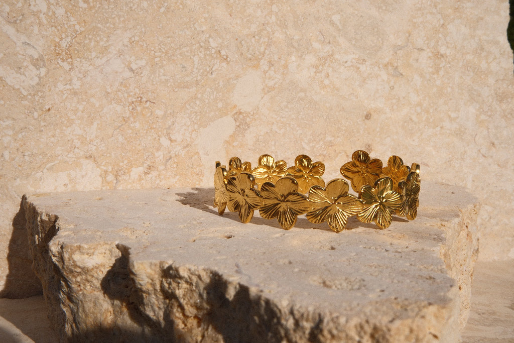 Gold bracelet on a stone surface with a stone wall background