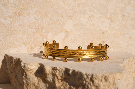 Gold bracelet on a stone surface with a beige stone background