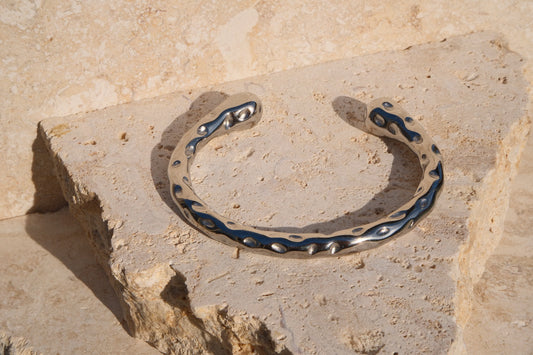Silver bracelet with blue accents on a stone surface
