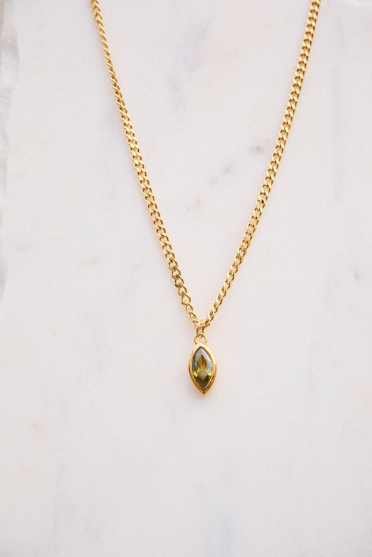 Gold necklace with a green gemstone pendant on a light background