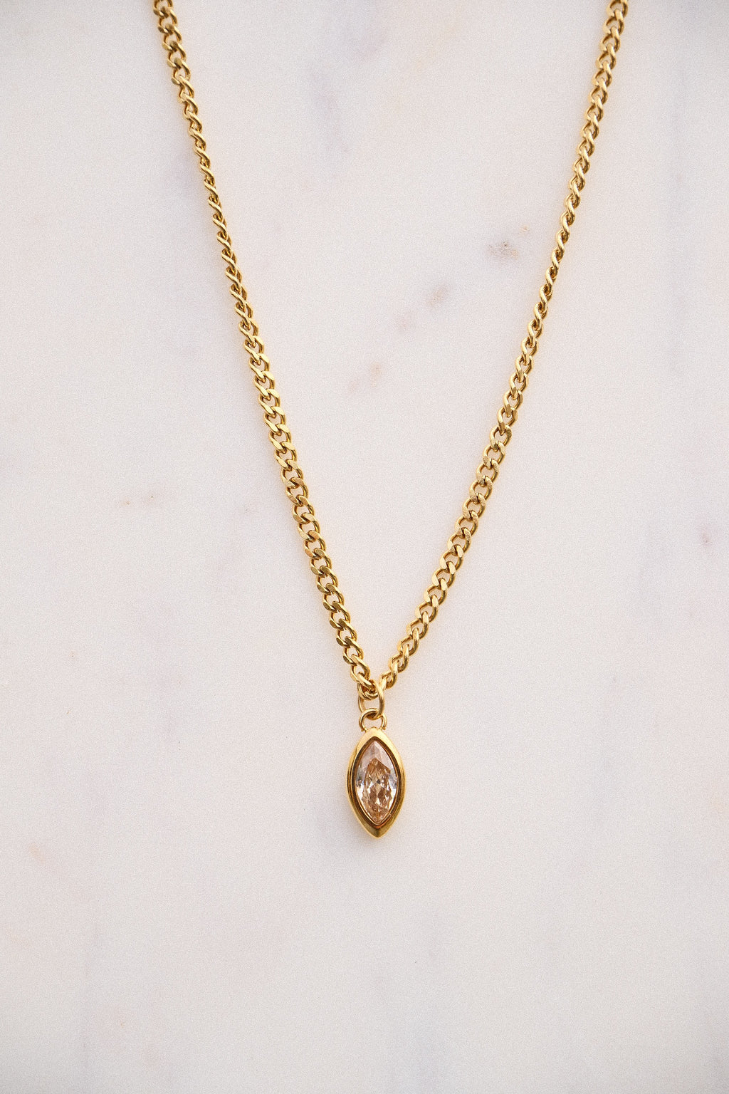 Gold necklace with a pendant on a light background