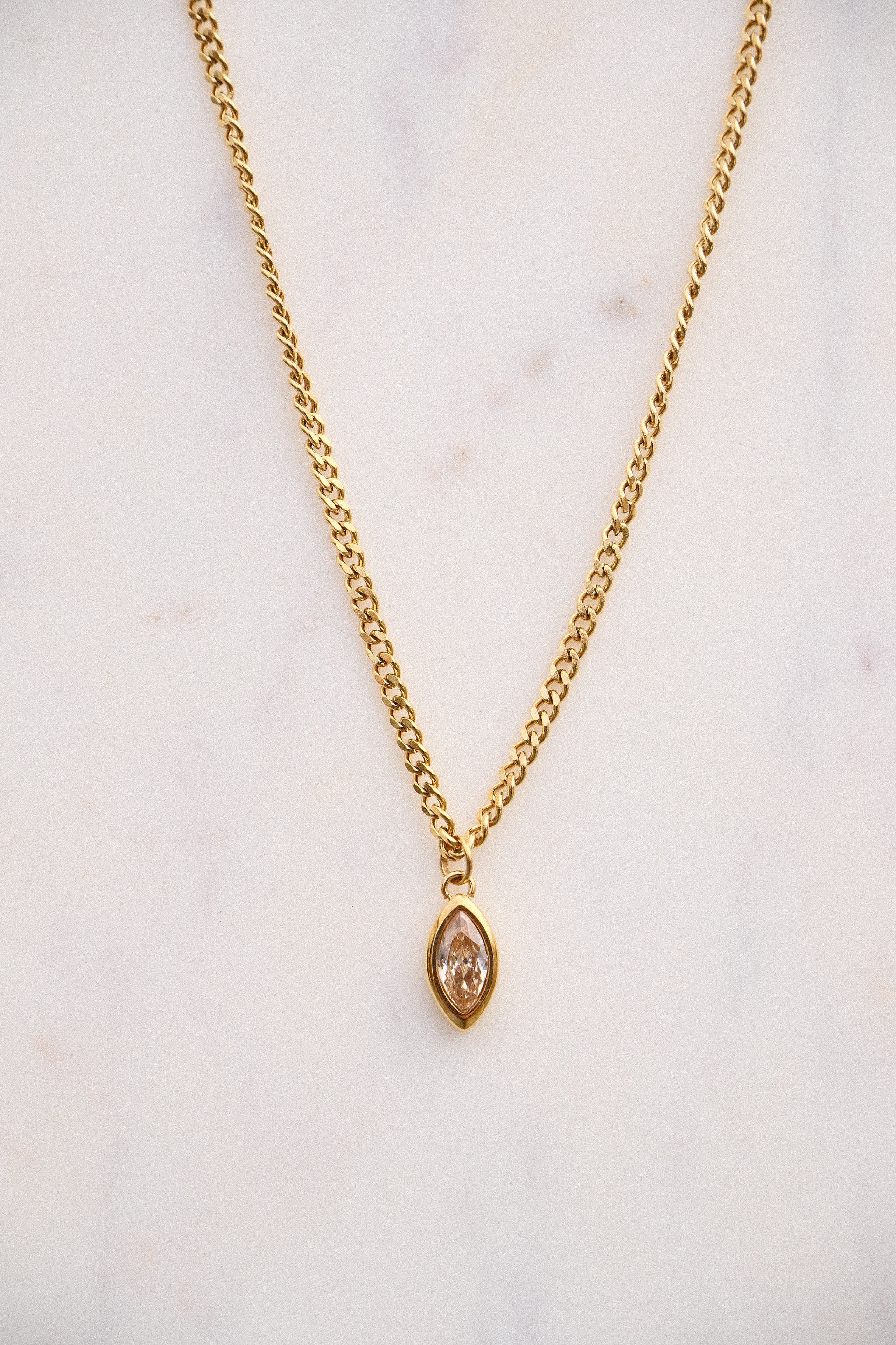 Gold necklace with a pendant on a light background