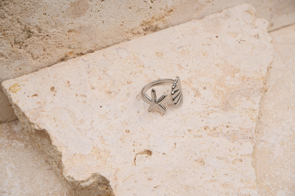 Silver ring with star design on a textured stone surface