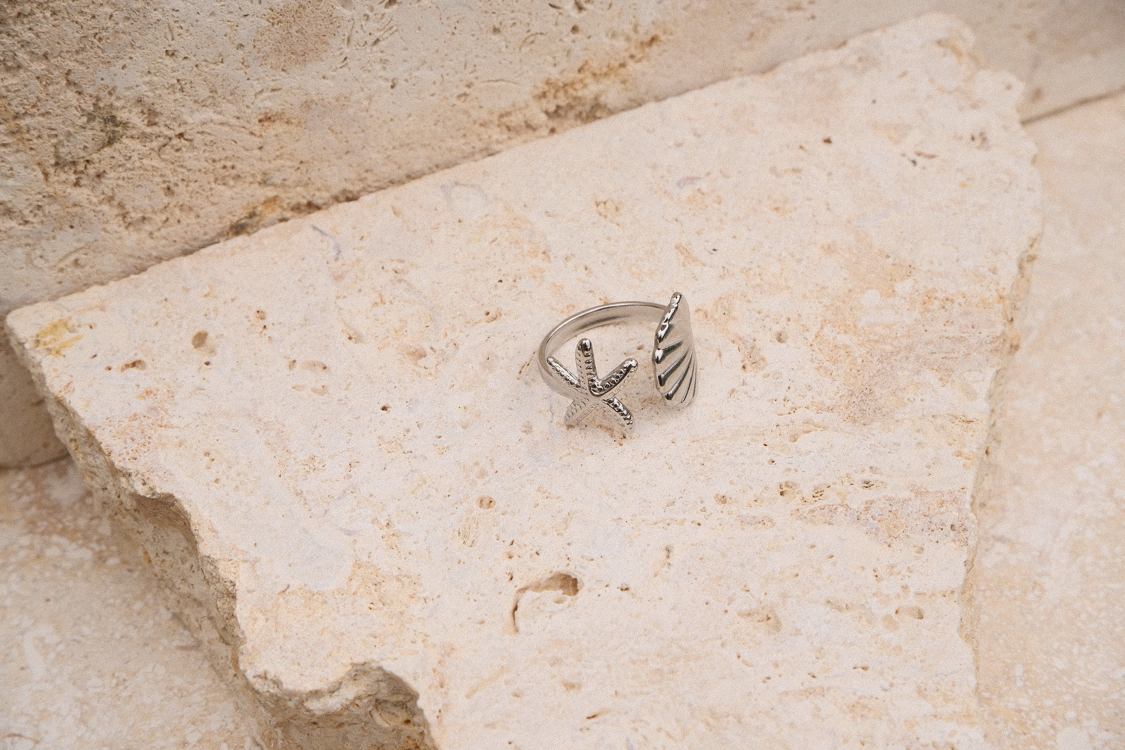 Silver ring with star design on a textured stone surface