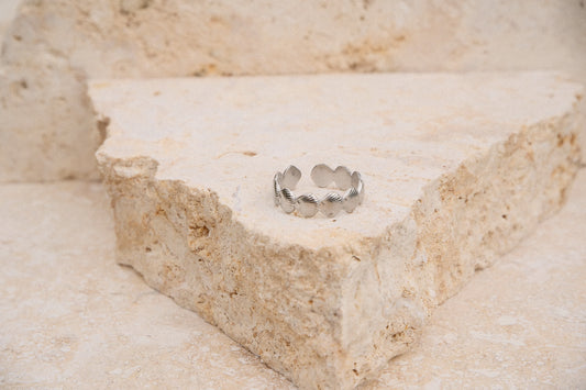 Silver ring on a textured beige stone surface