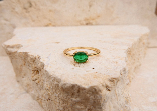 Gold ring with a green gemstone on a textured stone surface
