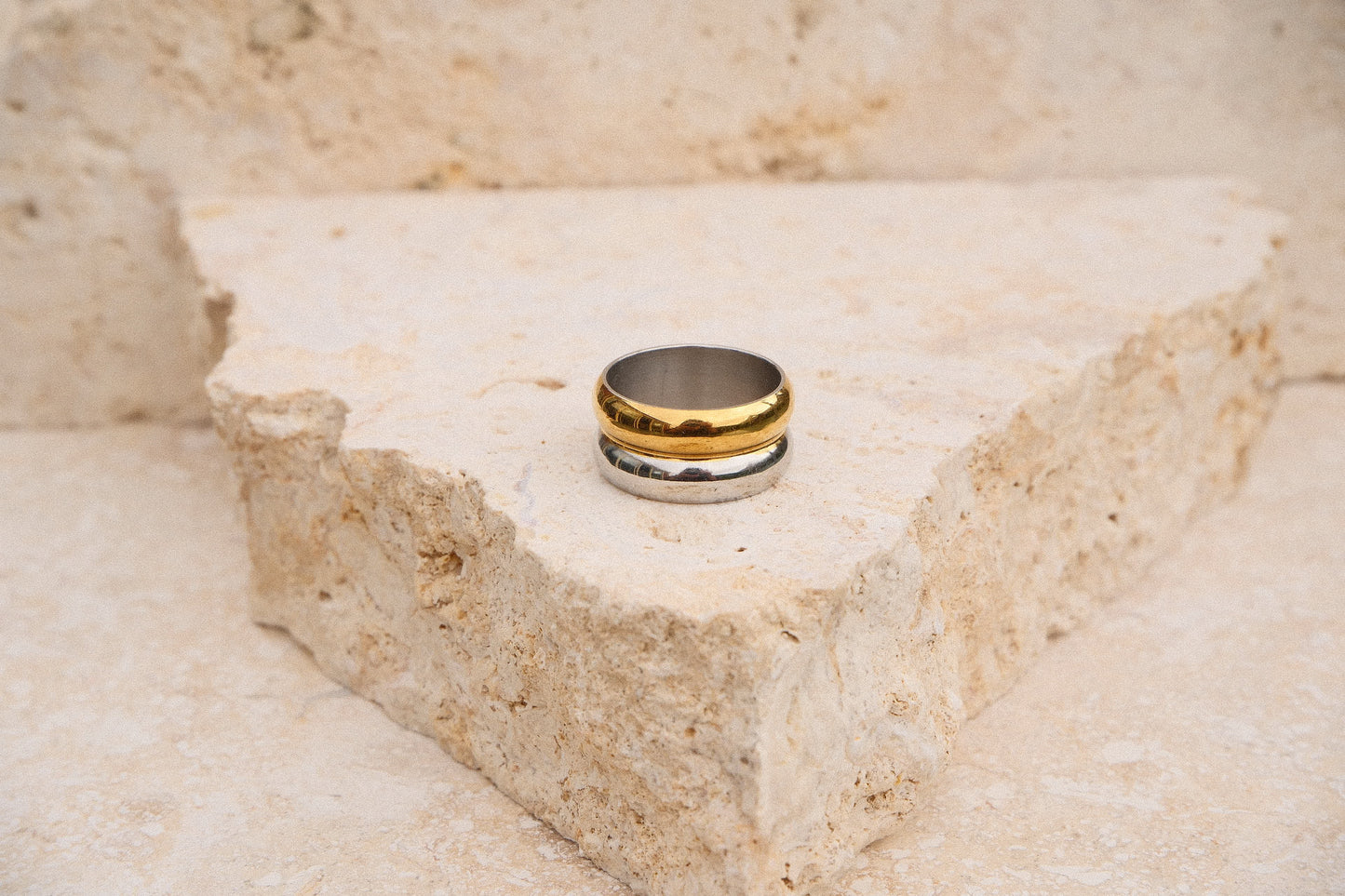 Gold and silver ring on a textured stone surface