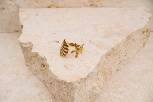 Gold starfish-shaped ring on a textured beige surface