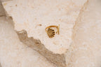 Gold ring on a textured beige surface