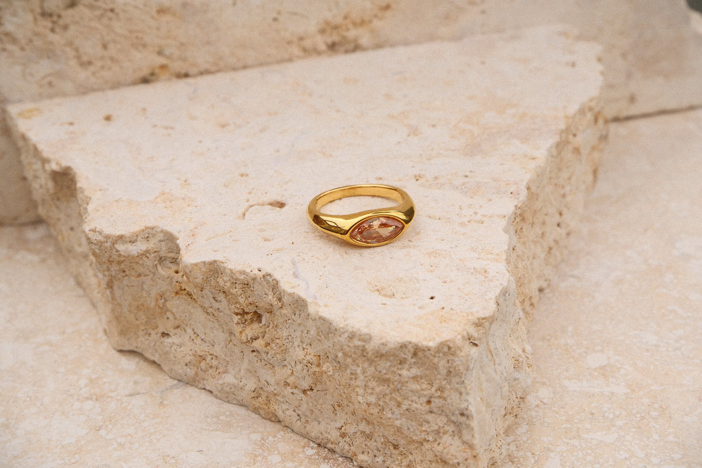 Gold ring with a stone on a textured stone surface