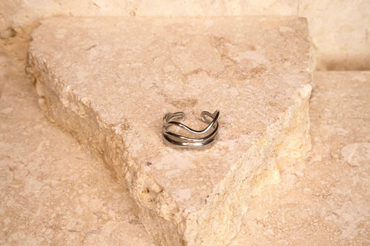 Silver ring on a textured beige stone surface