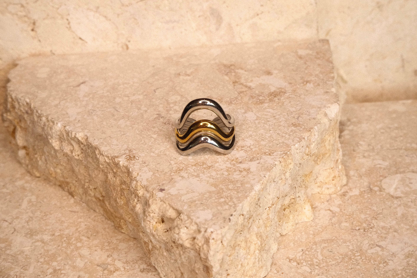 Silver ring with black and gold accents on a stone surface