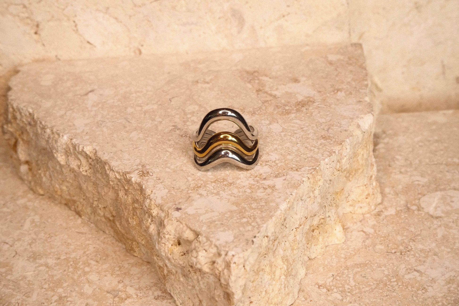 Silver ring with black and gold accents on a stone surface