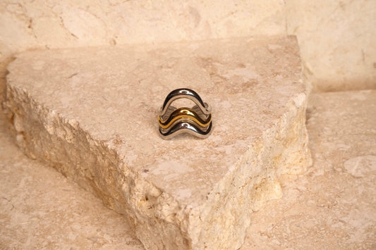 Silver ring with black and gold accents on a stone surface